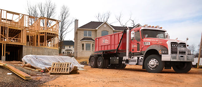 Residential dumpster and rolloff truck in front of house