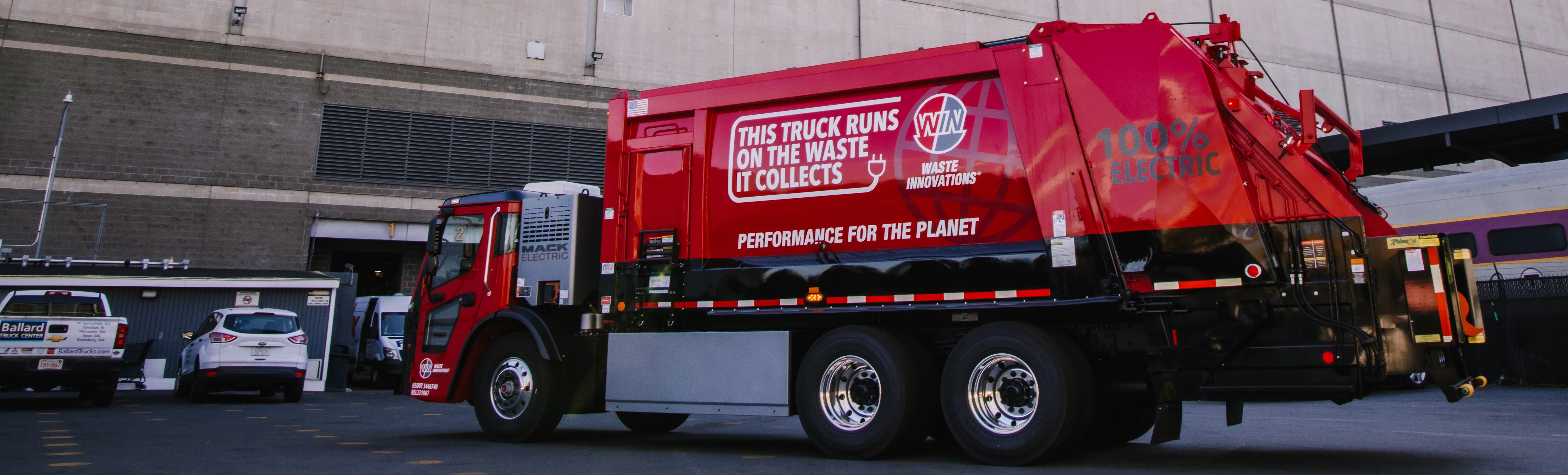 red electric trash truck owned by WIN Waste Innovations in front of the TD Garden in Boston, MA.